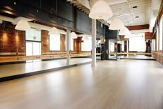 an empty room with wooden floors and large mirrors on the wall, along with lights hanging from the ceiling