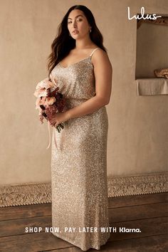 a woman in a gold sequin dress holding a bouquet of flowers and looking at the camera