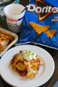 a white plate topped with lasagna next to a bag of doritos