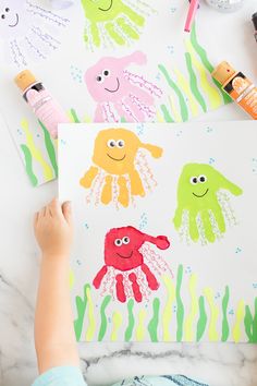 a child's hand is painting an octopus and jellyfish art project