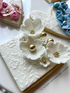 three decorated cookies sitting on top of a white plate next to flowers and hearts in the background