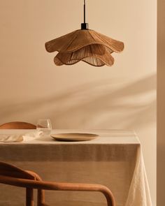 a dining room table with a plate, fork and knife under a bamboo light fixture