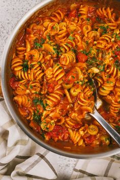 a pot filled with pasta and sauce on top of a table next to a towel