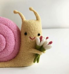 a close up of a stuffed animal with a flower in it's mouth and a snail on its back