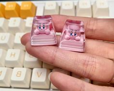 two tiny pink piggygies sitting on top of a computer keyboard in front of a person's hand