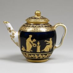 a black and gold teapot with figures on it