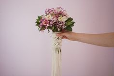 a person holding a bouquet of flowers in front of a pink wall with white trim