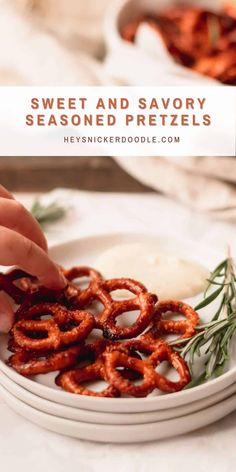 someone is dipping sauce on some pretzels in a white bowl with rosemary sprigs