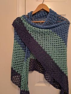 a blue and green crocheted shawl hanging on a door