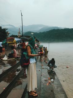 a woman standing in the rain with an umbrella over her head and other people around her