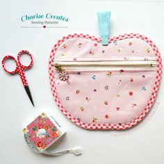 a heart shaped purse with scissors and tape next to it on a white table top