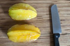 two pieces of yellow fruit sitting next to a knife