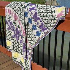 a crocheted blanket draped over a wooden railing