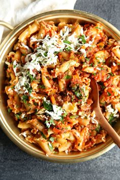 a bowl filled with pasta and meat covered in parmesan cheese, on top of a table