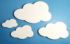 four white clouds on a blue background with one cloud shaped like a cat and the other as a dog