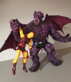 two action figures are posed next to each other on a white surface, one is purple and the other is yellow