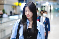 a woman with long black hair standing in an airport