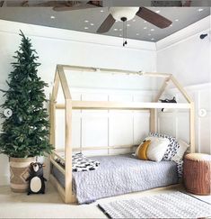 a bedroom with a bed and a christmas tree in the corner, next to a toy penguin