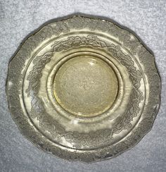 a silver plate sitting on top of a gray tablecloth covered floor next to a white wall