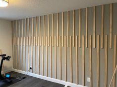 an exercise room with wooden slats on the wall and a treadmill in front of it