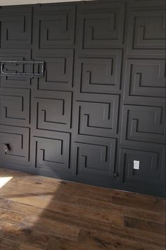 an empty room with black painted walls and wood floors