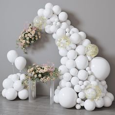 white balloons and flowers are arranged in the shape of a letter g on a wall