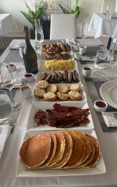 a long table filled with breakfast foods and glasses of wine on top of the table