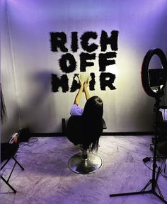 a woman sitting on top of a chair in front of a wall with the words rich off hair