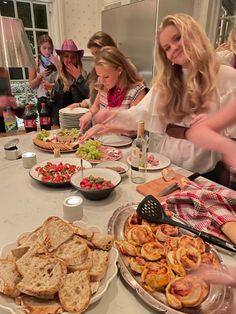 a group of women standing around a table filled with food