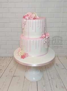 a three tiered cake with pink icing and flowers