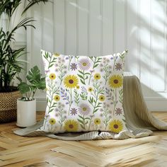 a white pillow sitting on top of a wooden floor next to a potted plant