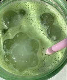 a green drink with ice and a pink straw