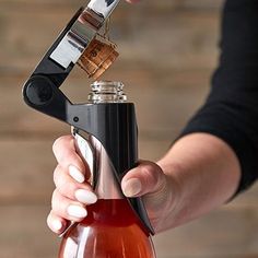 a person is holding a bottle with some wine in it and an opener on the top