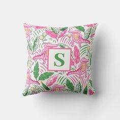 a pink and green tropical print pillow with the letter s on it's front