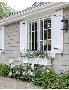 an image of a house with flowers in the window boxes