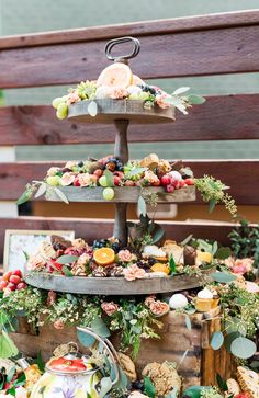 a three tiered tray with fruit and flowers on it