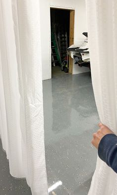 a person is looking through the curtains in a room