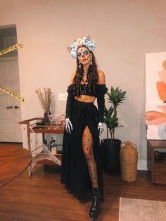 a woman dressed up as a skeleton with flowers in her hair and makeup is posing for the camera