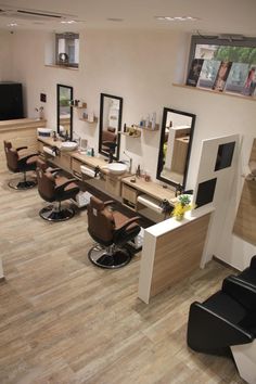 a hair salon with chairs, mirrors and pictures on the wall above it's sinks