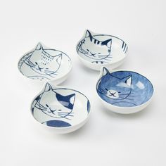 four blue and white bowls with cats painted on them