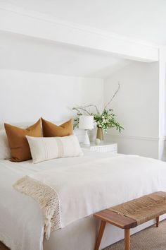 a bed with white sheets and pillows in a bedroom