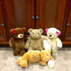 four stuffed animals sitting on the floor in front of wooden cabinets