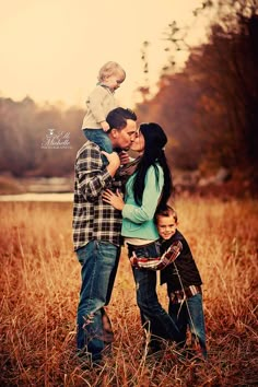 a man, woman and child are standing in the tall grass with their arms around each other