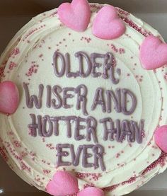 a white cake with pink frosting and hearts on it that says older, wise and hotter than ever