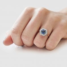 a woman's hand with a blue and white diamond ring on her left finger