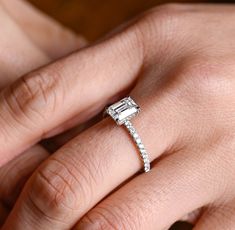 a woman's hand with a diamond ring on her left hand and the other hand holding an engagement ring