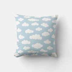 a blue pillow with white clouds printed on the front and back, sitting against a wall