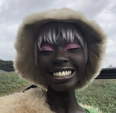 a woman with white hair and pink eyes is wearing a hood over her head while smiling