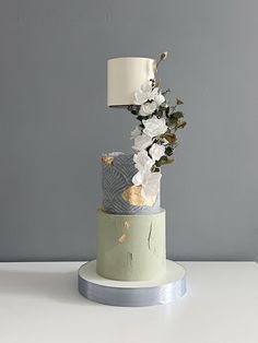 a three tiered cake with white flowers on top and a lamp in the middle