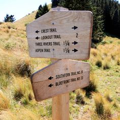 a wooden sign pointing in different directions on the side of a hill